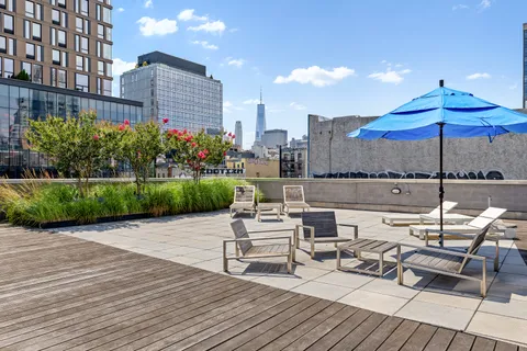 a view of a rooftop with chairs and tables in the patio