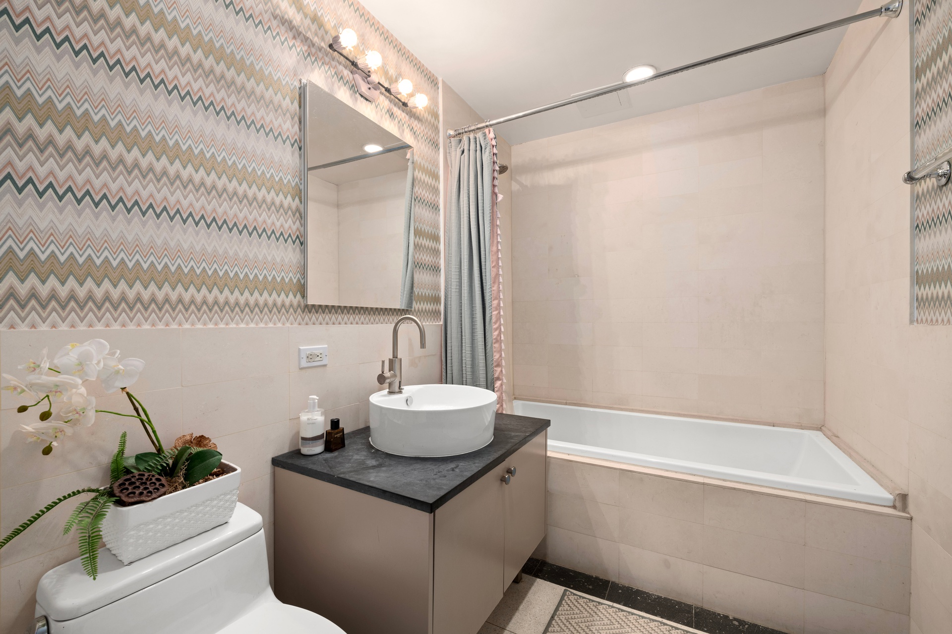 26 Broadway, Unit 602 Brooklyn, NY 11249 - Photo 7 of 12 a bathroom with a granite countertop sink a mirror and a bathtub