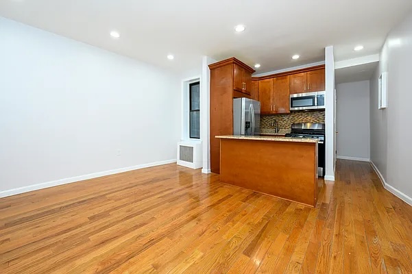 237 West 135th Street, Unit 3A Manhattan, NY 10030 - Photo 3 of 12 a view of a kitchen with kitchen island a sink wooden floor and stainless steel appliances