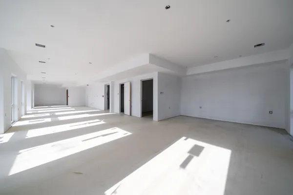 a view of a big room with wooden floor and windows