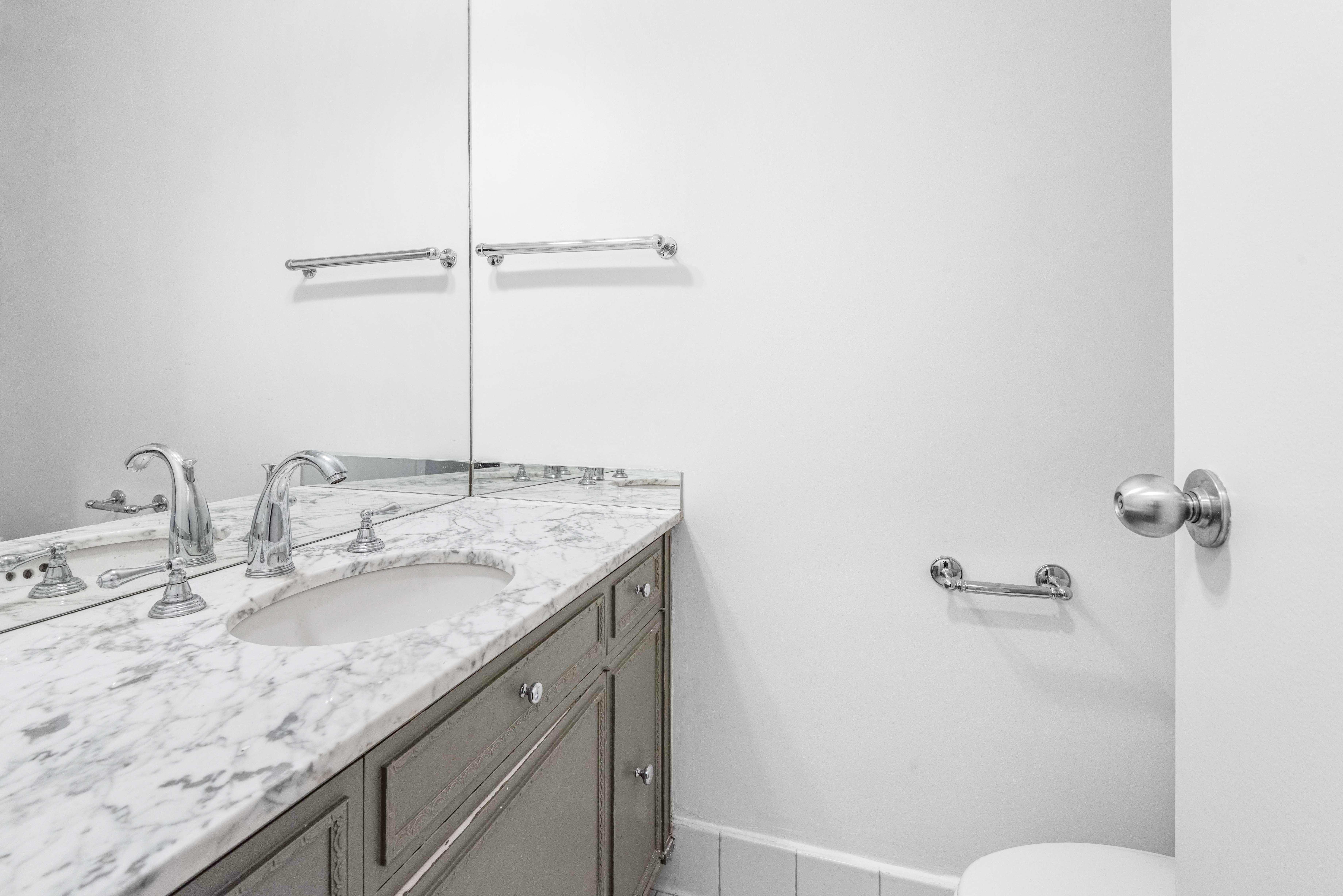 175 East 62nd Street, Unit 12A Manhattan, NY 10065 - Photo 13 of 24 a bathroom with a granite countertop sink toilet and shower