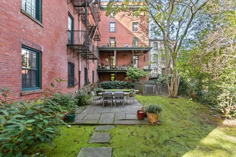 a view of a brick house with a yard and plants