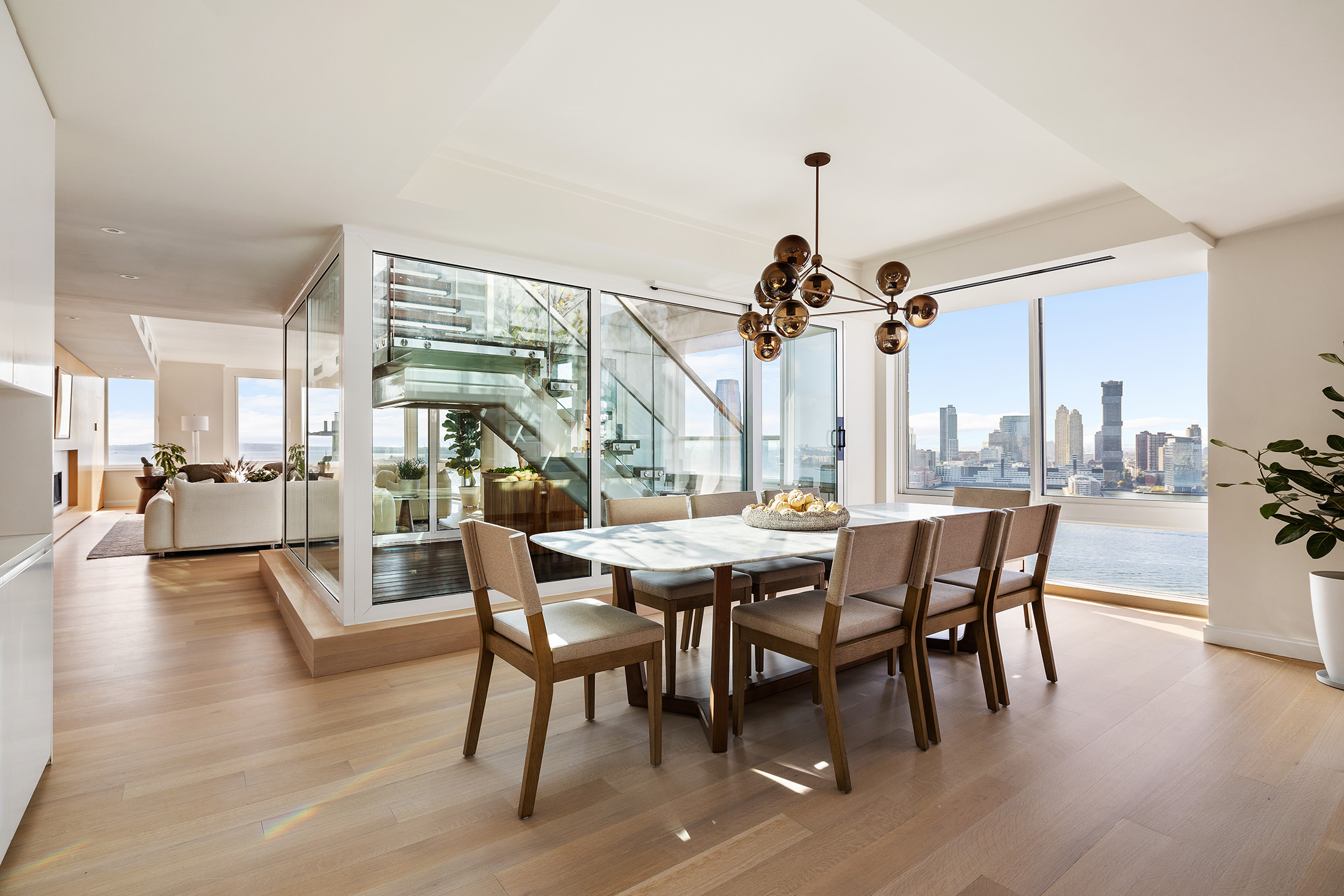 212 Warren Street, Unit PHS Manhattan, NY 10282 - Photo 6 of 18 a dining room with wooden floor a chandelier a glass table and chairs