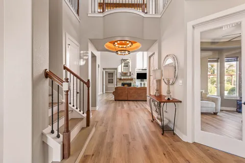 a kitchen with stainless steel appliances kitchen island granite countertop a refrigerator a stove and a sink with wooden floor