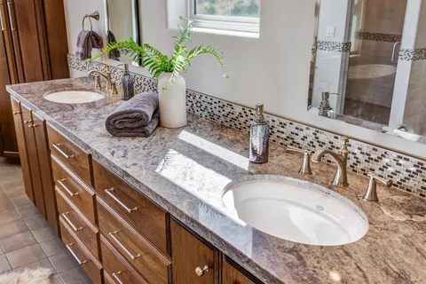 a bathroom with a granite countertop tub sink and mirror