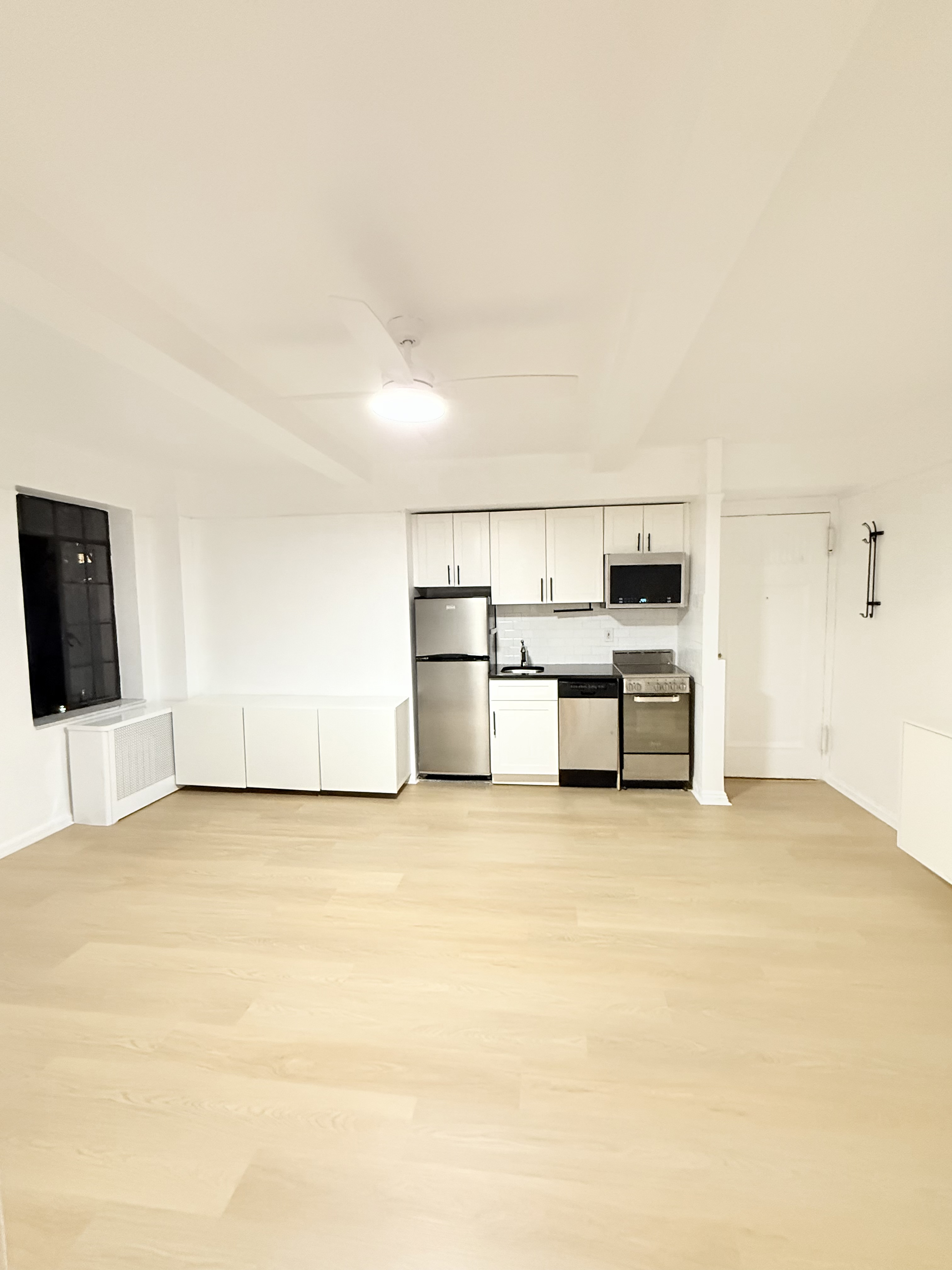 45 Tudor City Place, Unit 418 Manhattan, NY 10017 - Photo 2 of 11 a view of kitchen with stainless steel appliances refrigerator stove microwave and cabinets