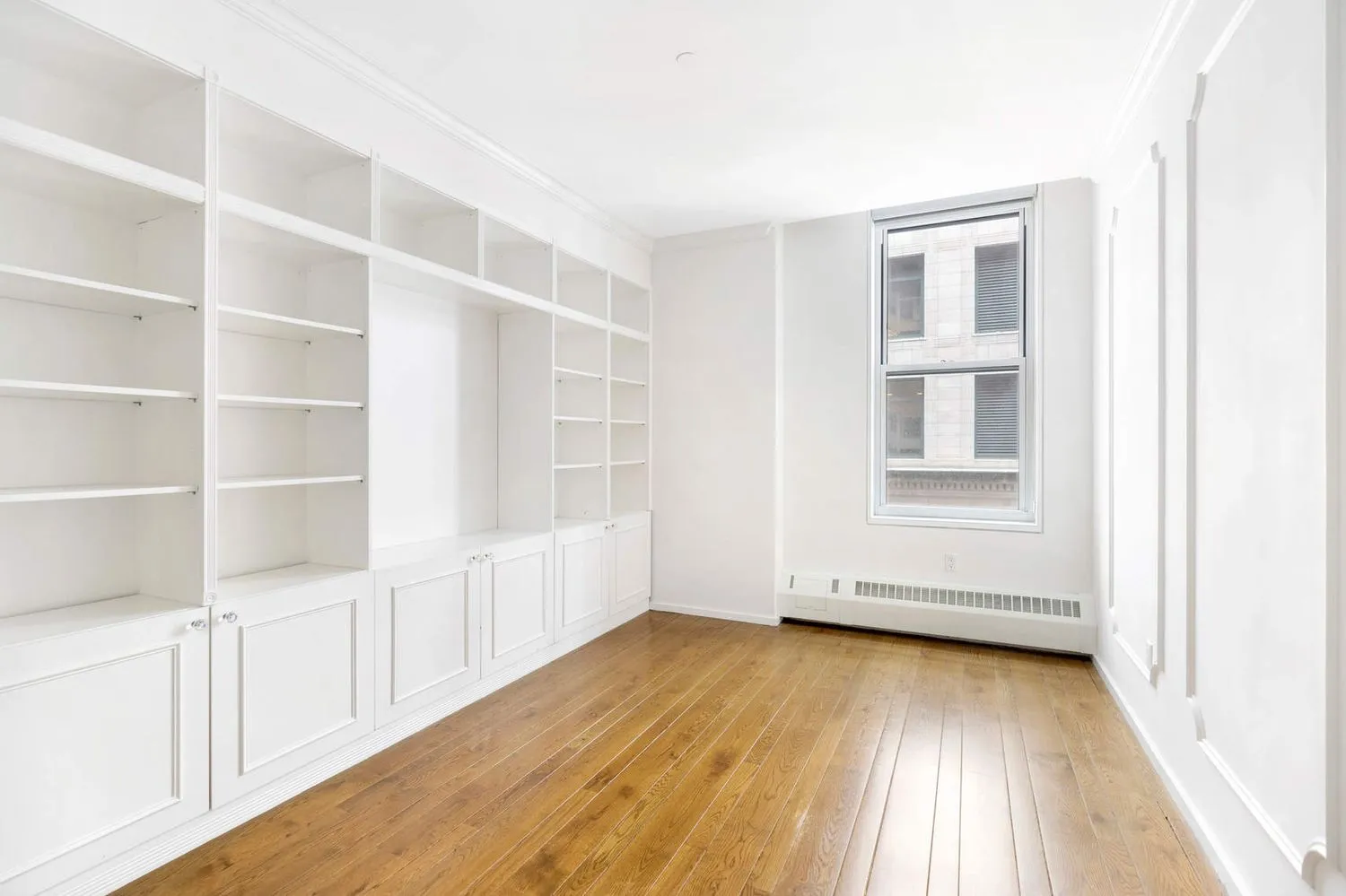 a view of an empty room with a window and wooden floor