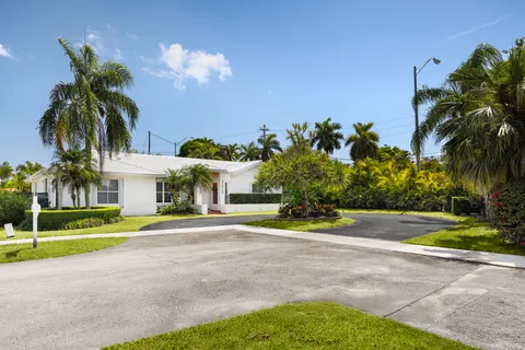 a front view of a house with a yard and palm trees