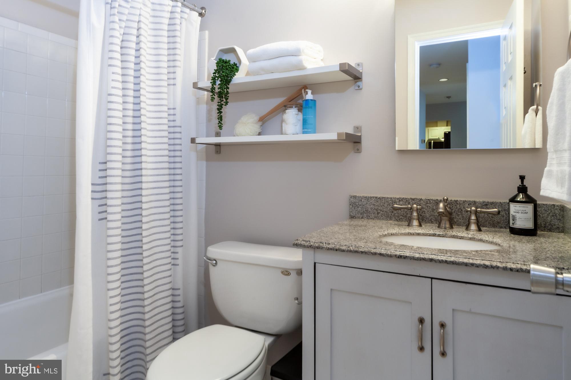 1715 15th Street Northwest, Unit 101 Washington, DC 20009 - Photo 7 of 23 a bathroom with a granite countertop toilet sink and mirror