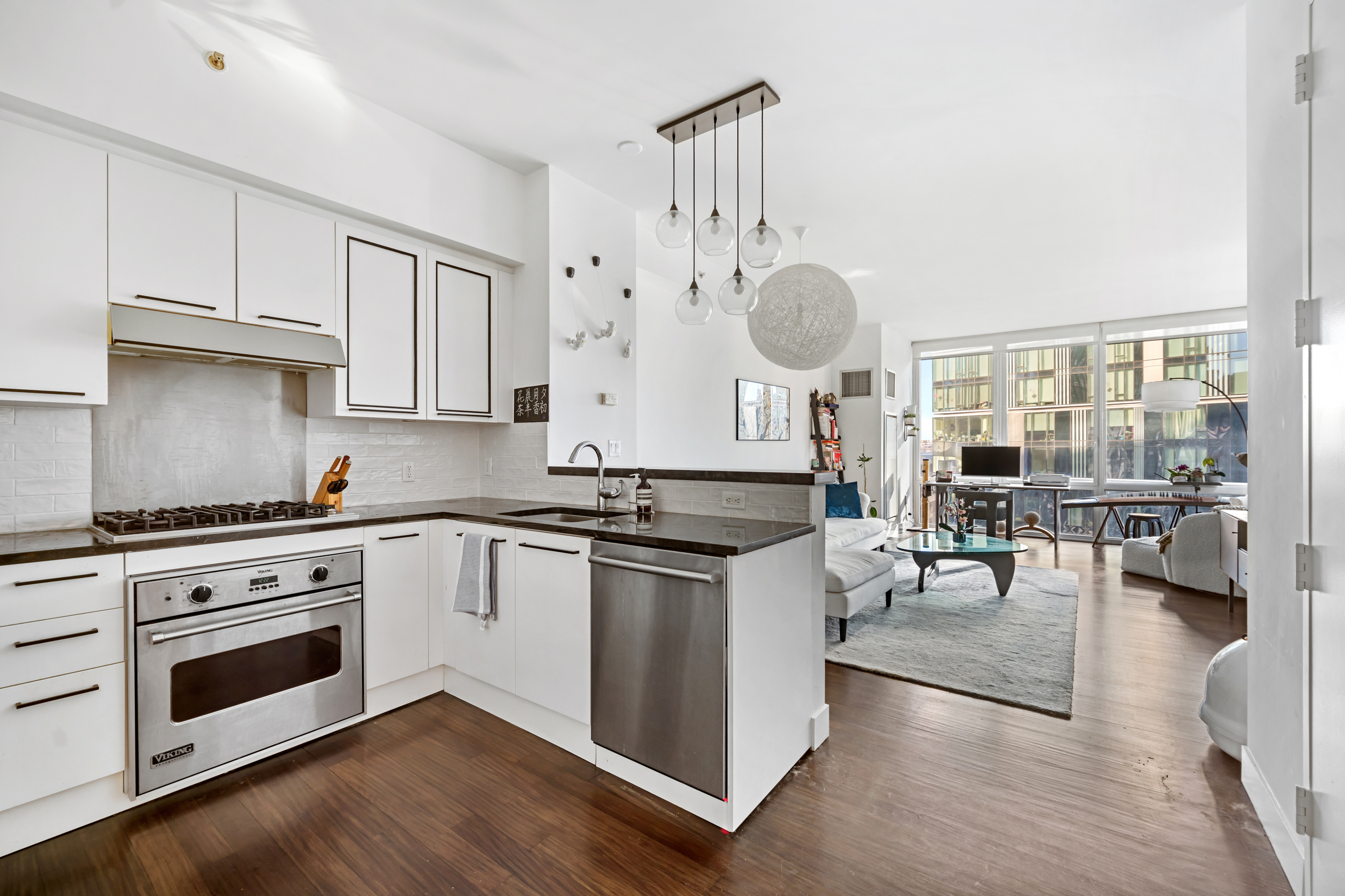 a kitchen with stainless steel appliances granite countertop a stove and white cabinets with wooden floor