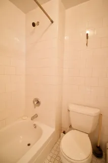 a white toilet sitting next to a bath tub and a shower