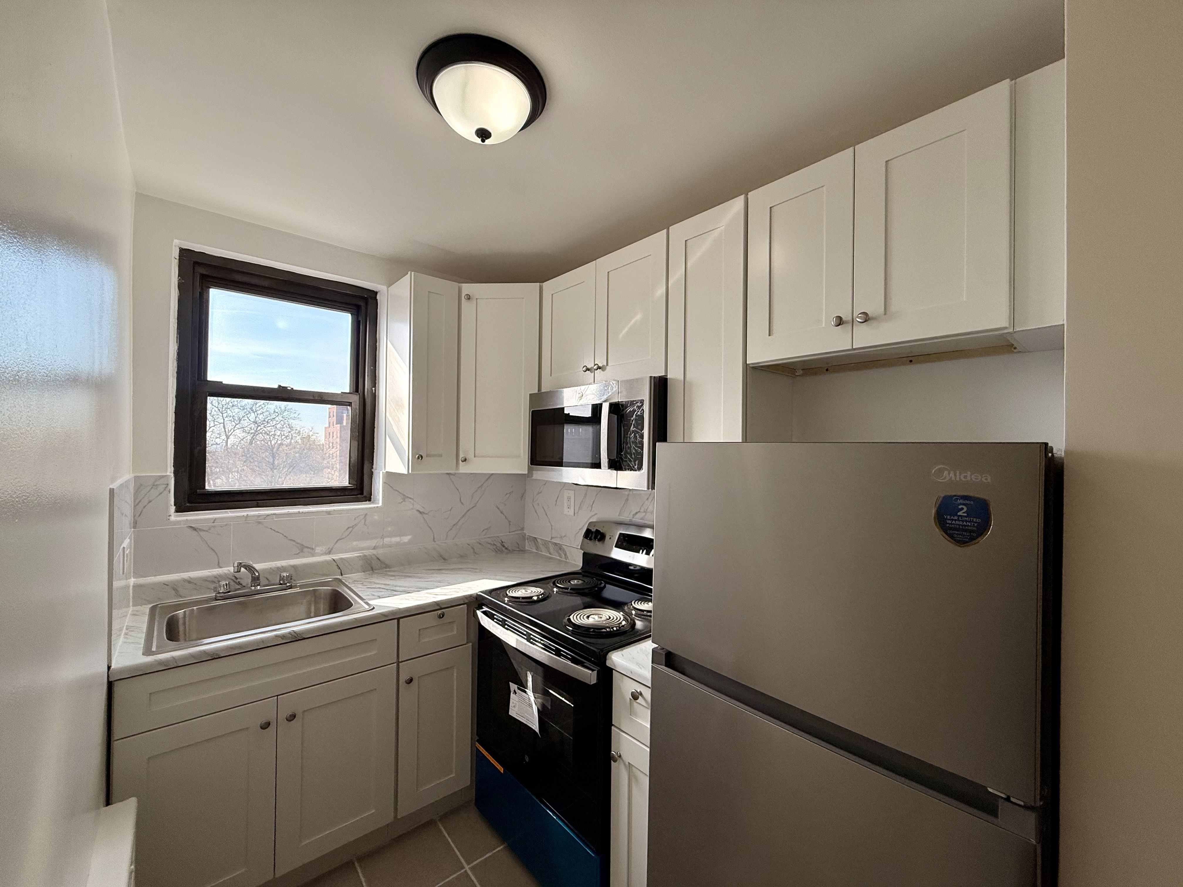 230 73rd Street, Unit 4B Brooklyn, NY 11209 - Photo 2 of 9 a kitchen with granite countertop a sink stainless steel appliances and white cabinets