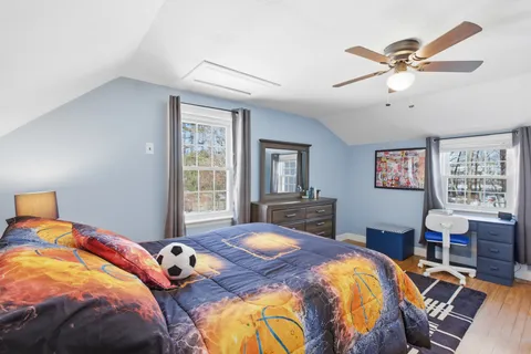 a bedroom with a bed and dresser with wooden floor