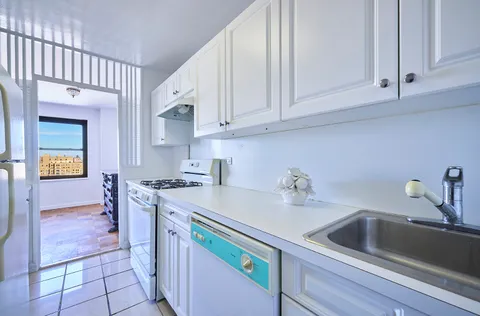 a kitchen with white cabinets and sink