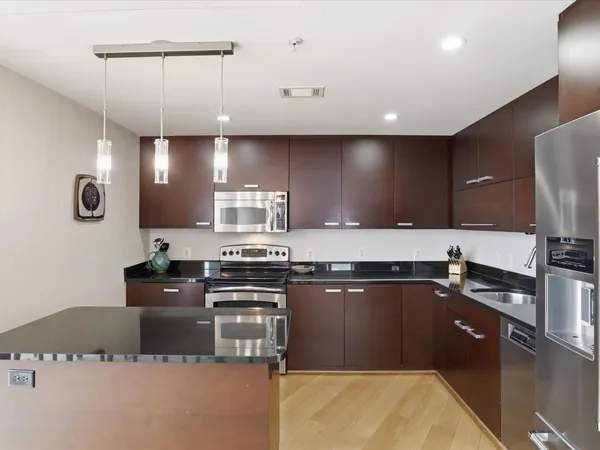 a large kitchen with granite countertop a sink stainless steel appliances and cabinets