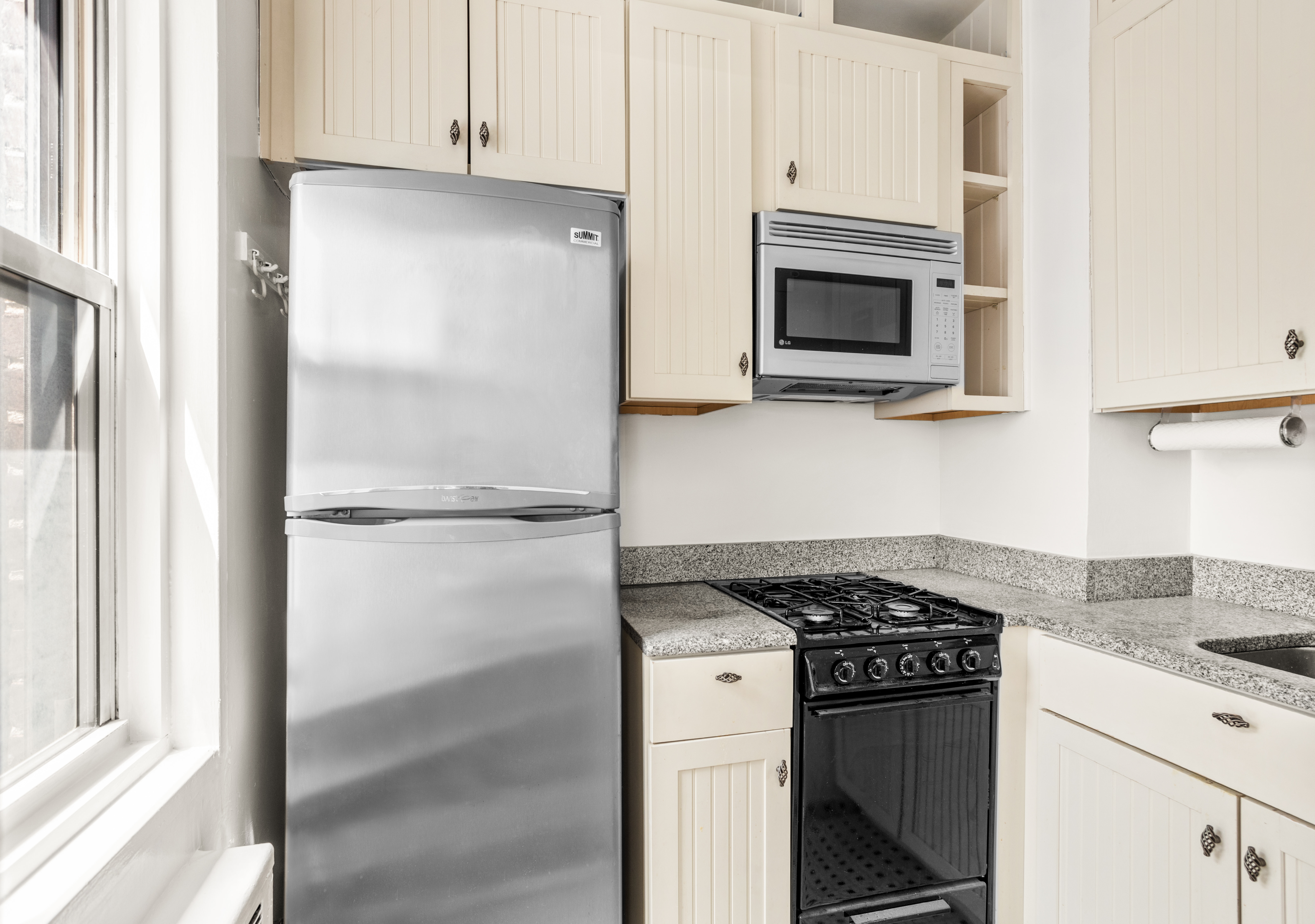 310 East 49th Street, Unit 7B Manhattan, NY 10017 - Photo 5 of 10 a kitchen with a refrigerator stove and microwave