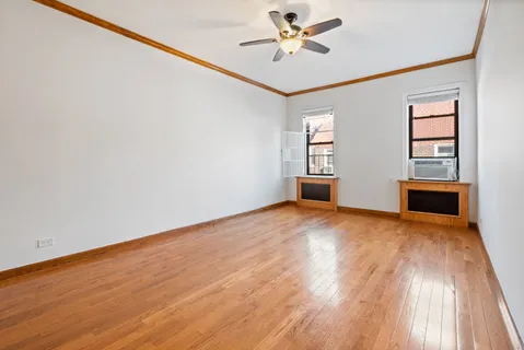 a view of empty room with wooden floor and fan