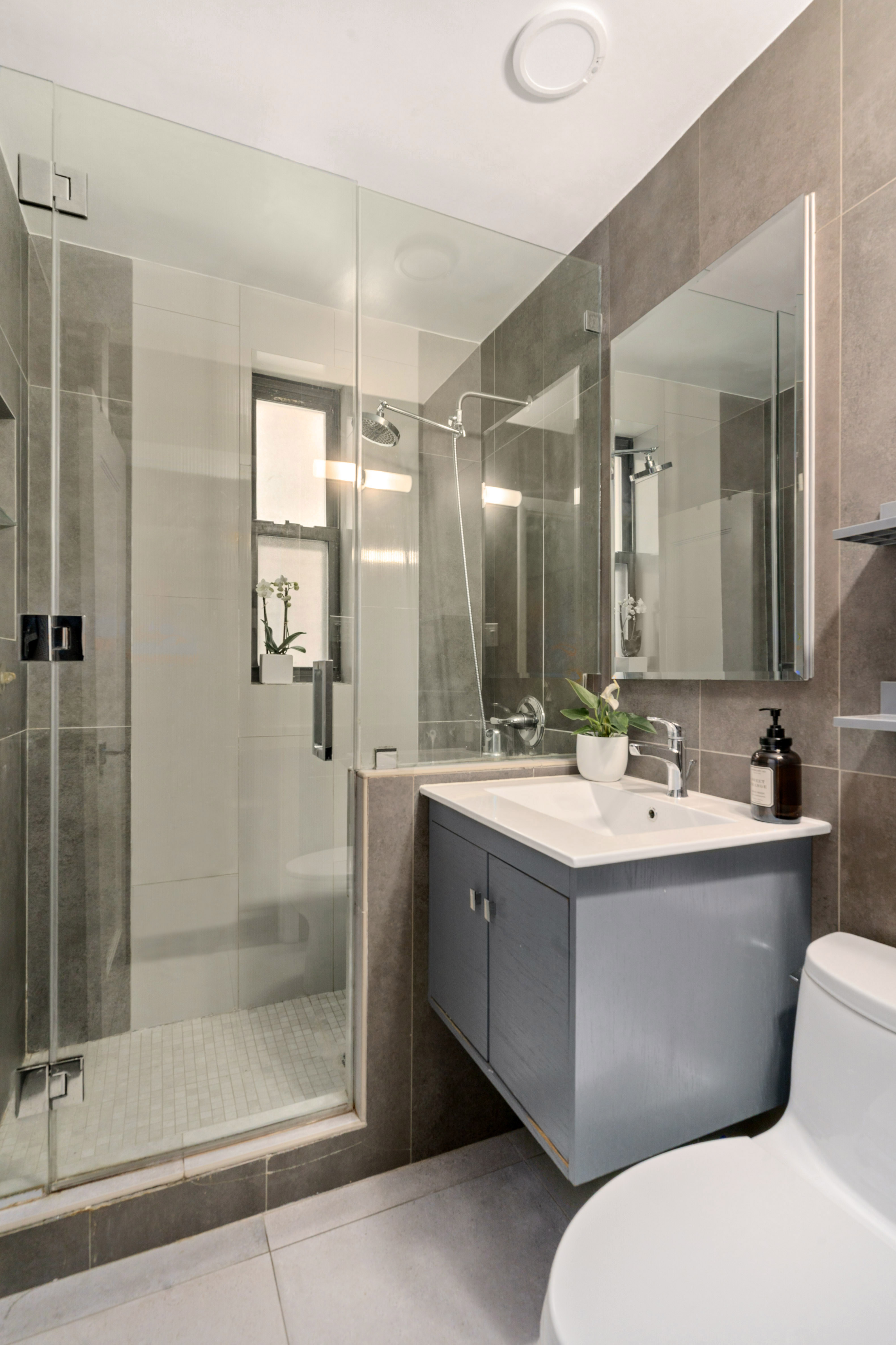 100 Bank Street, Unit 1A Manhattan, NY 10014 - Photo 5 of 6 a bathroom with a mirror a toilet sink and shower