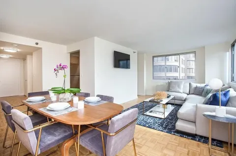 a living room with furniture a flat screen tv and a window