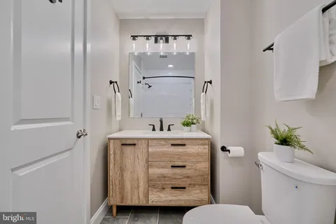 a bathroom with a granite countertop sink a toilet and shower