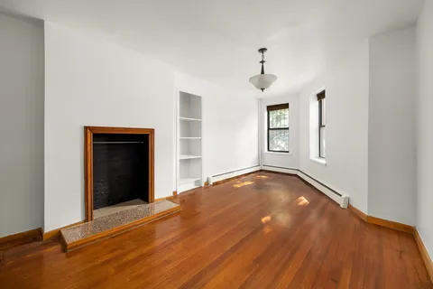 a view of empty room with wooden floor and ceiling fan