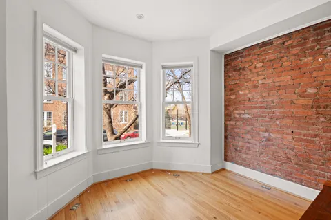 a view of an empty room with a window and wooden floor