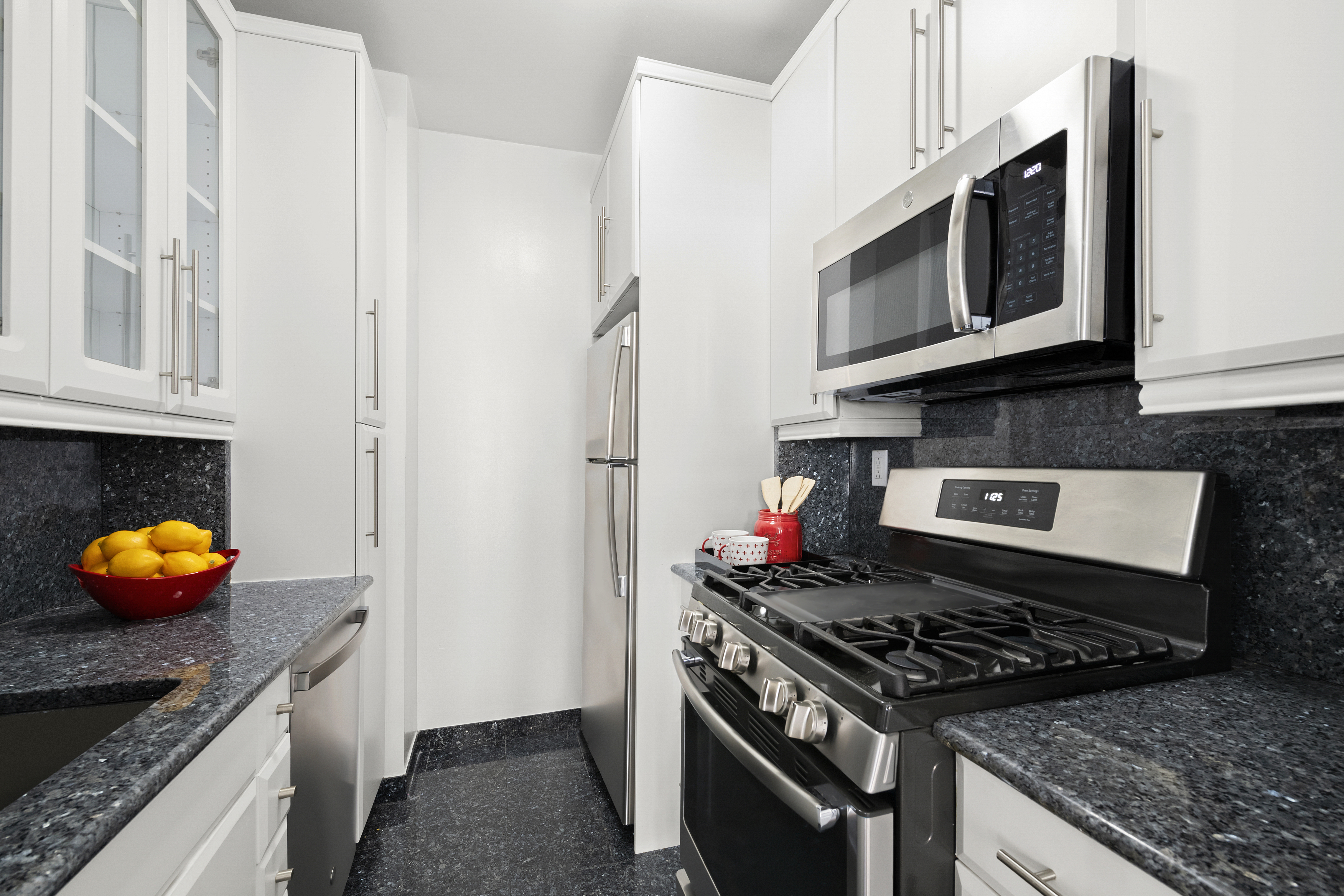 304 East 65th Street, Unit 6D Manhattan, NY 10065 - Photo 6 of 15 a kitchen with stainless steel appliances granite countertop a stove a microwave and a refrigerator