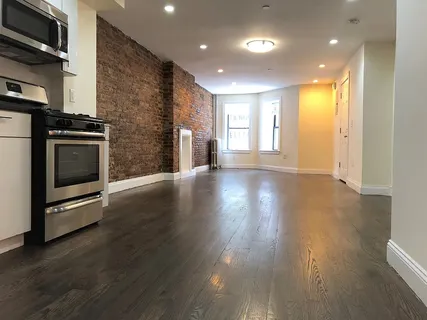 a view of an empty room with wooden floor and a fireplace
