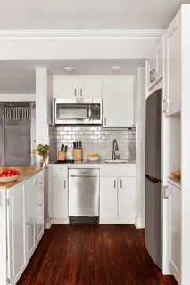 a kitchen with stainless steel appliances a refrigerator a sink and wooden floors