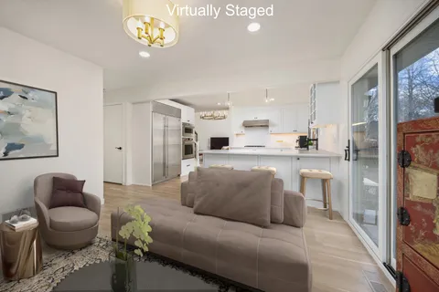 a living room with stainless steel appliances furniture a rug and a view of kitchen