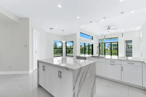 a large white kitchen with granite countertop a sink and dishwasher with a large window