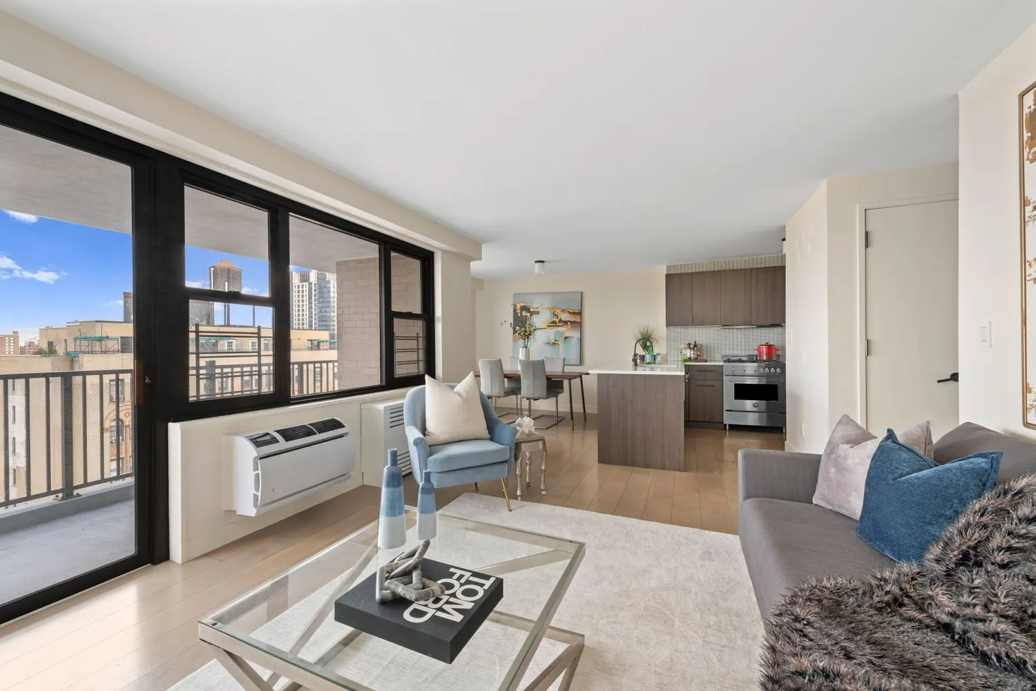 a living room with furniture a rug kitchen view and a large window