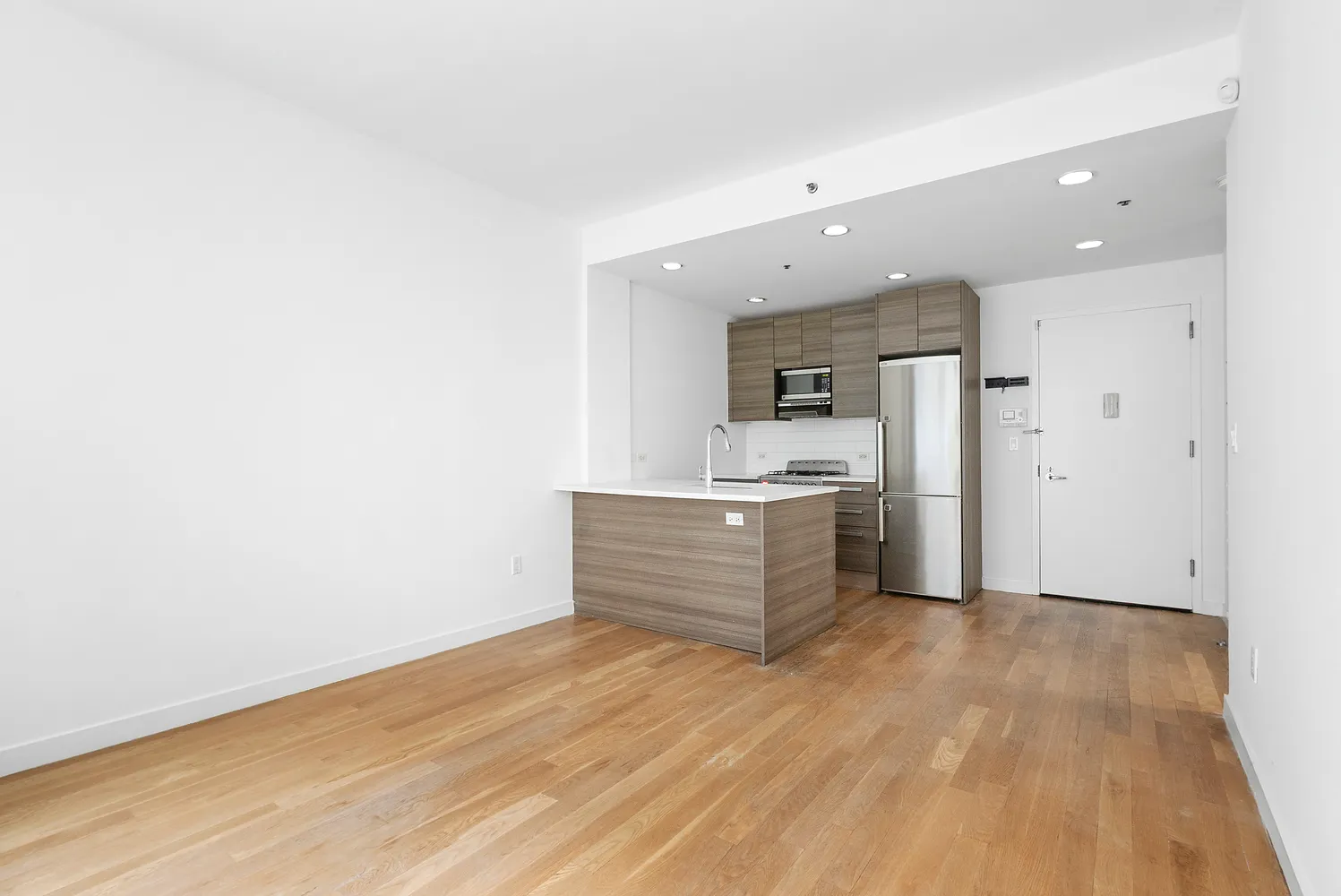 a view of a kitchen with white cabinets and wooden floor