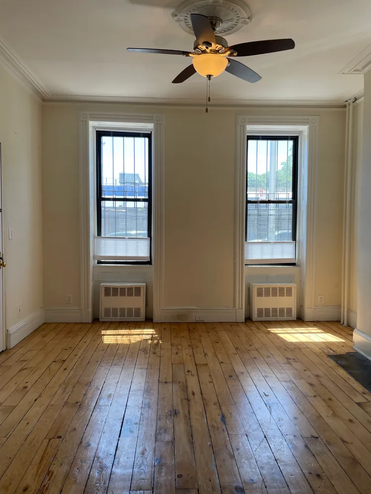 an empty room with wooden floor and windows