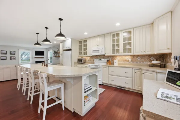 a kitchen with stainless steel appliances granite countertop a stove top oven a refrigerator a sink and a dining table with wooden floor