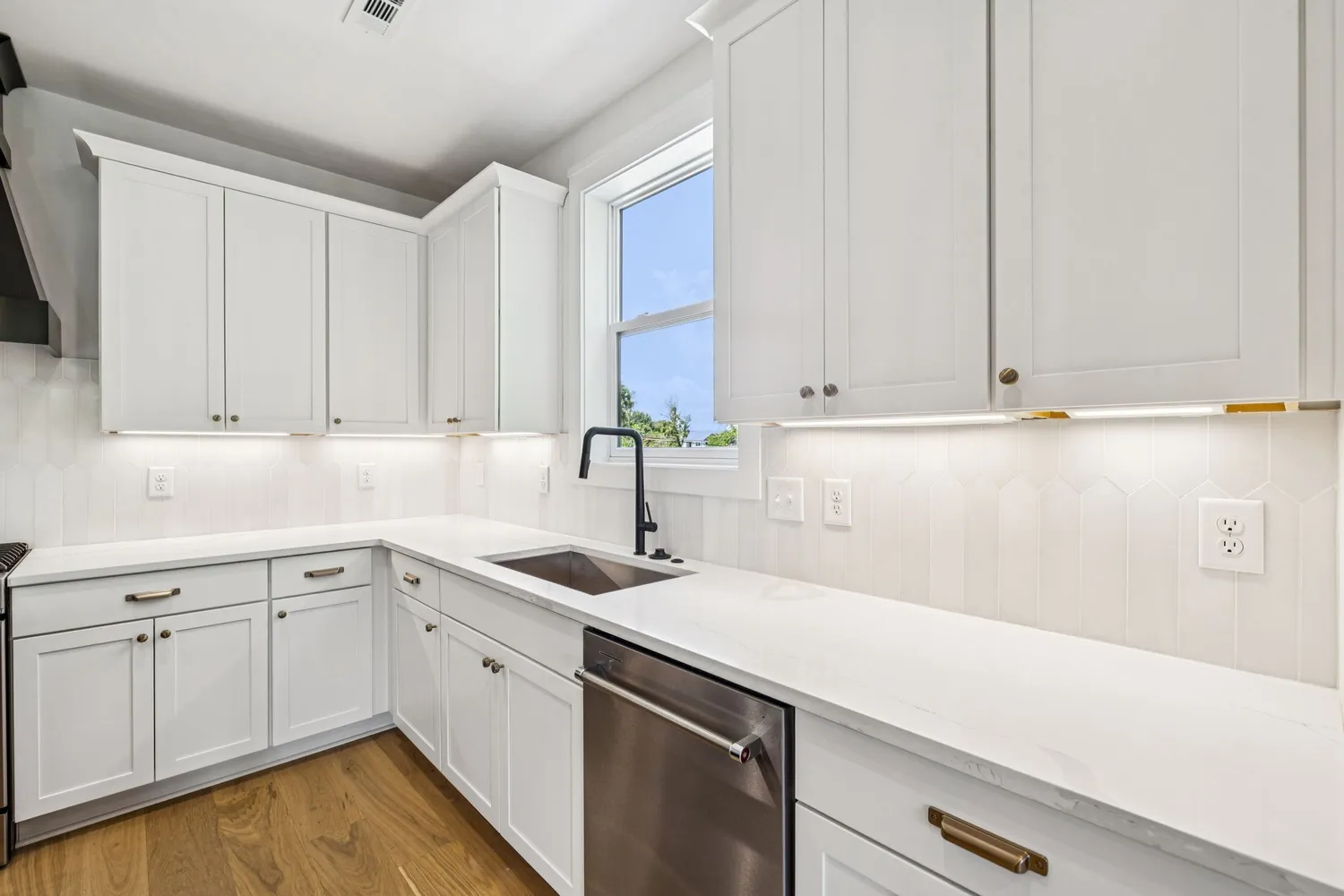 a utility room with stainless steel appliances white cabinets and a sink