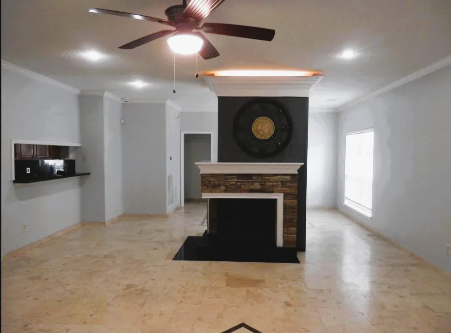 a view of an empty room with a fireplace and fan