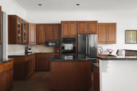a kitchen with granite countertop stainless steel appliances a refrigerator a sink a stove cabinets and furniture