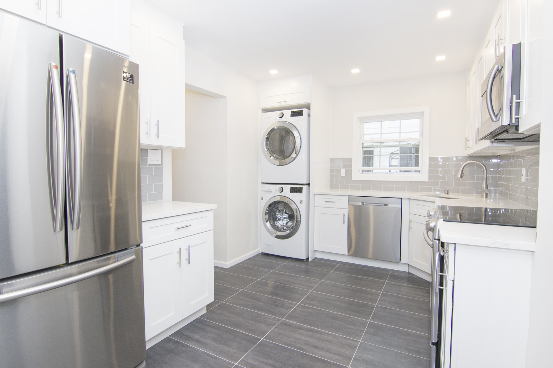 a kitchen with stainless steel appliances granite countertop a refrigerator a stove and a sink with large window