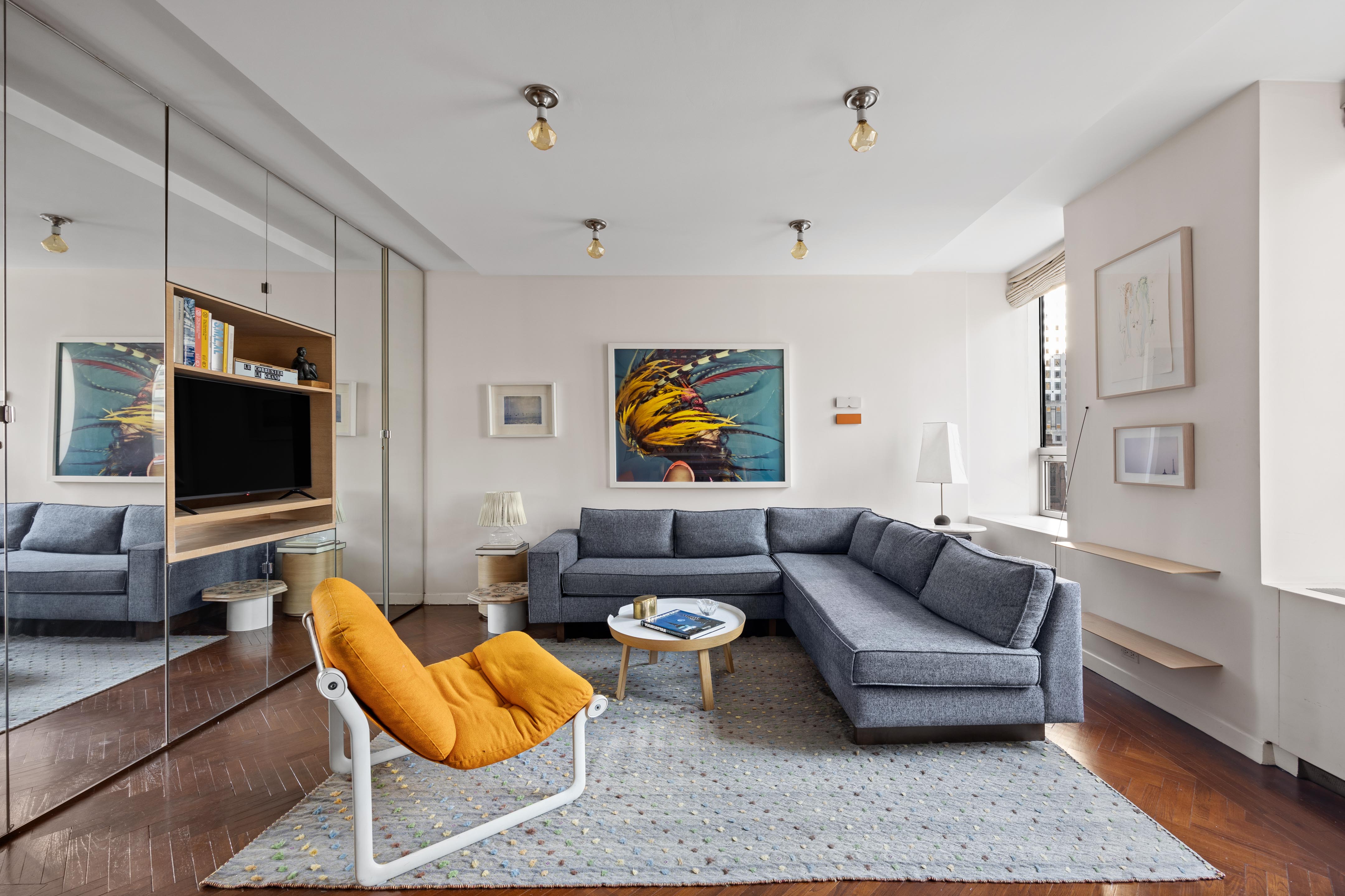15 West 53rd Street, Unit 10H Manhattan, NY 10019 - Photo 3 of 11 a living room with furniture and a flat screen tv