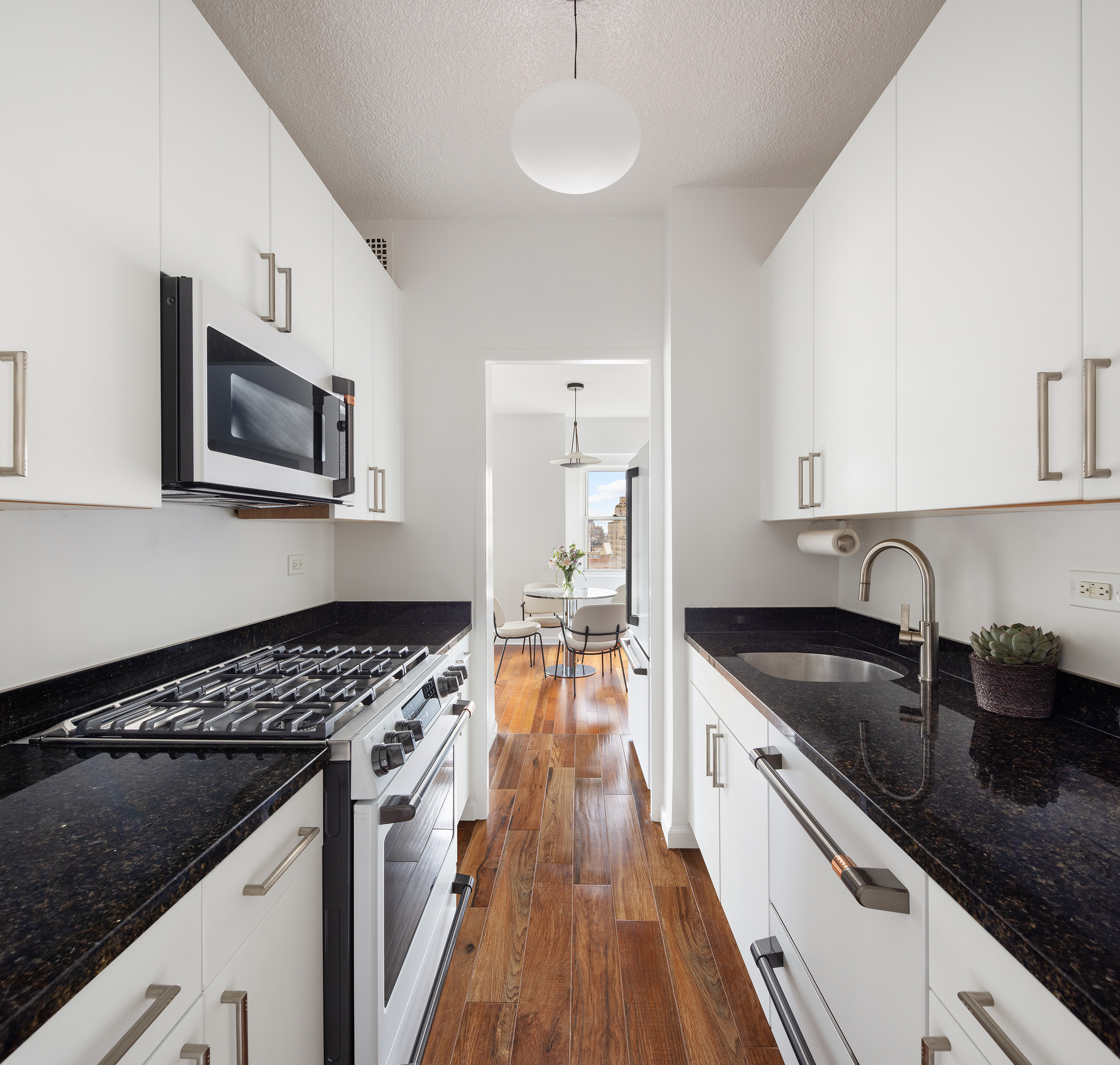 60 East 8th Street, Unit 10E Manhattan, NY 10003 - Photo 4 of 13 a kitchen with granite countertop a sink stove top oven and cabinets