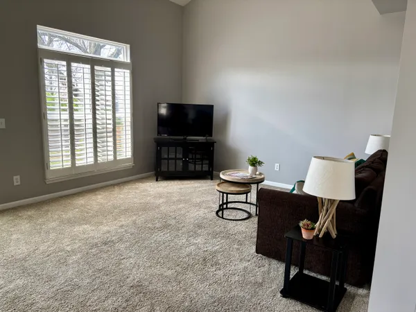 a living room with furniture a flat screen tv and a window