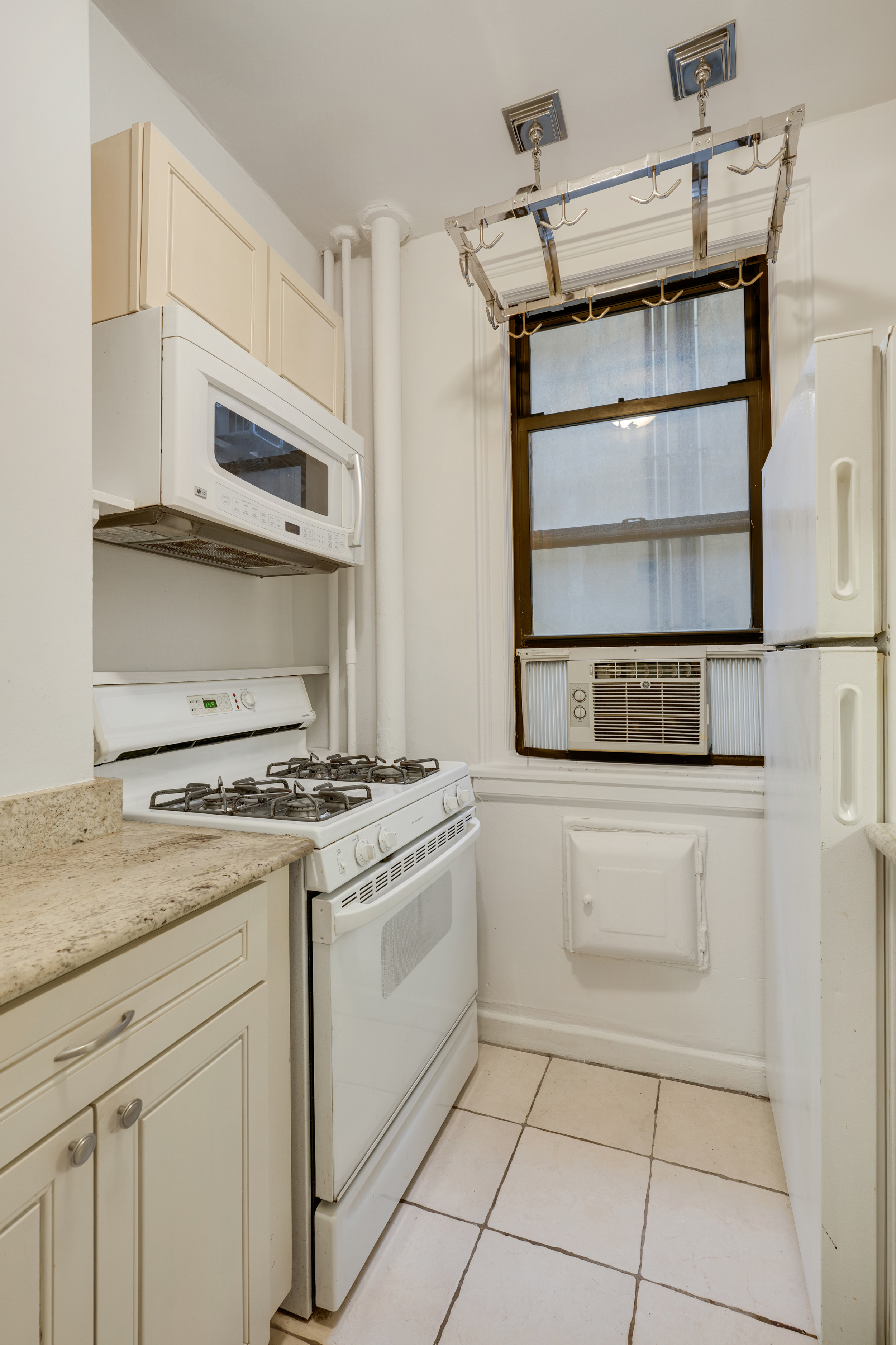 74 West 68th Street, Unit 5A Manhattan, NY 10023 - Photo 5 of 25 a kitchen with white cabinets and appliances