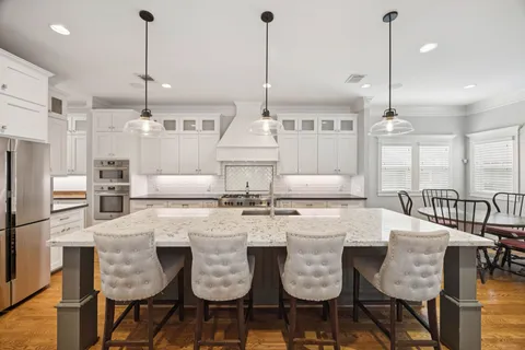 a kitchen with stainless steel appliances kitchen island granite countertop a table chairs and white cabinets