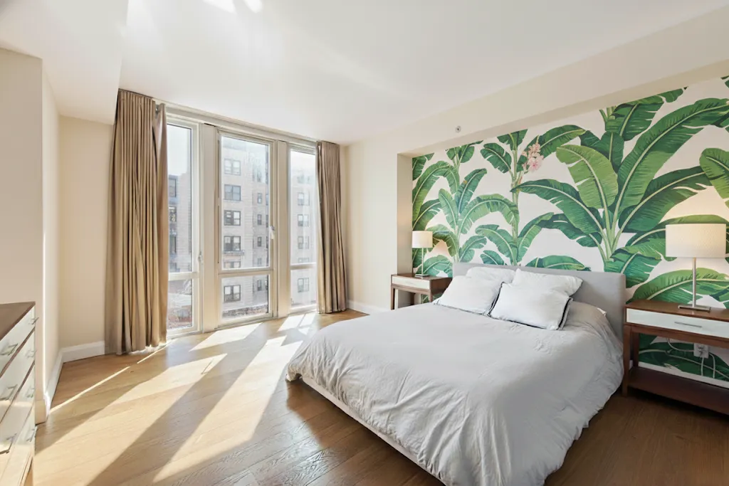 a bedroom with a large bed and a large window with potted plants