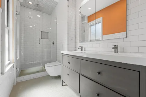 a bathroom with a double vanity sink a toilet and shower