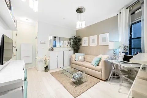 a living room with furniture a flat screen tv and a refrigerator