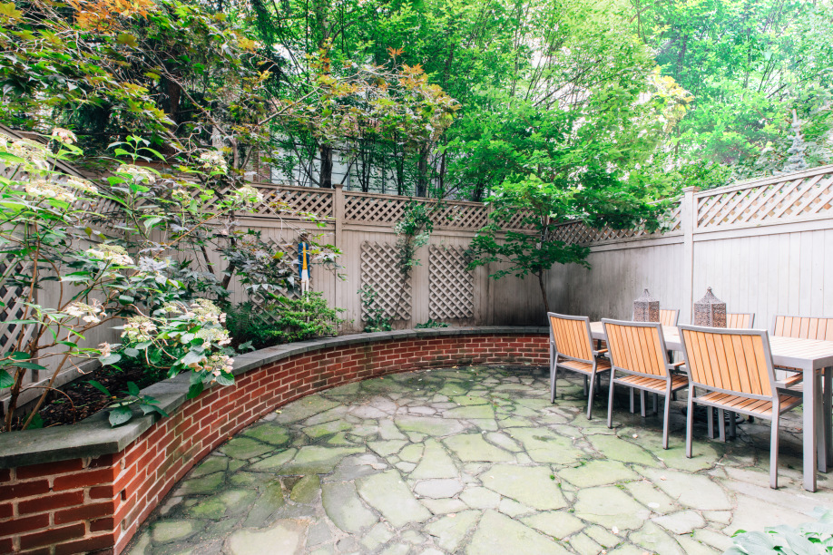 a backyard of a house with large trees and plants
