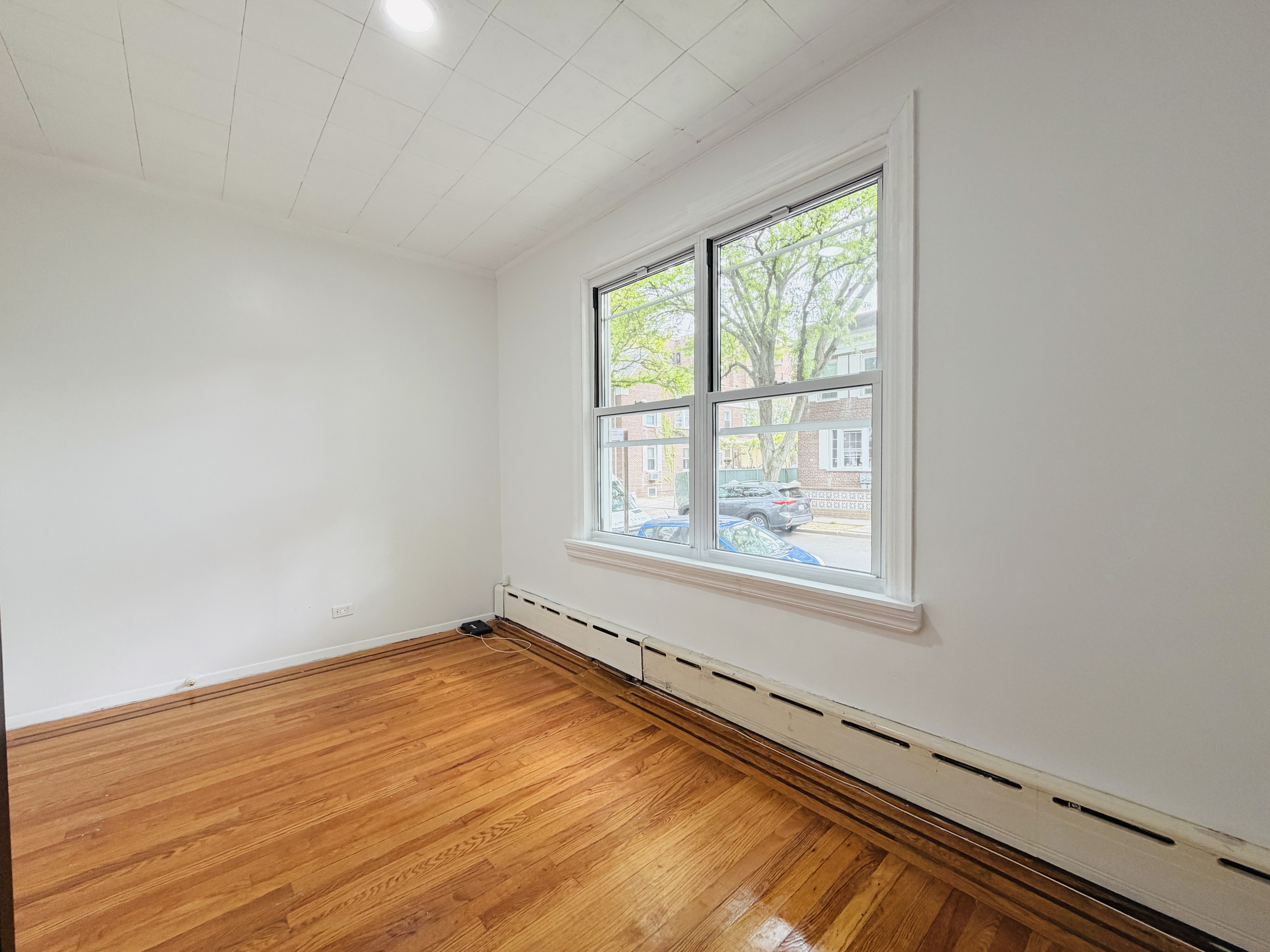 63-33 Haring Street, Unit 1F Queens, NY 11374 - Photo 12 of 13 a view of an empty room with wooden floor and a window