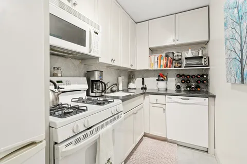 a kitchen with stainless steel appliances granite countertop white cabinets and white stove